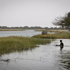 Mensch sitzt im Wasser am Ufer des Tschadsee