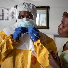Ein Mitarbeiter zieht sich die Schutzausrüstung an, bevor er das Ebola-Transitzentrum in Bunia, Demokratische Republik Kongo betritt. Mitarbeiter in Schutzausrüstung vor Ebola-Transitzentrum