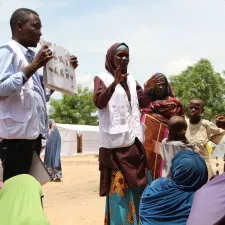 Mitarbeiter*innen der Gesundheitsförderung sprechen mit Vertriebenen in einem Camp in Borno