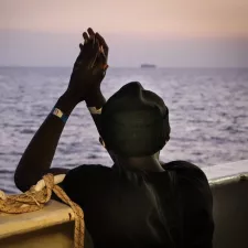 An der Reling der Sea Watch 4 schaut eine gerettete Person aufs Meer