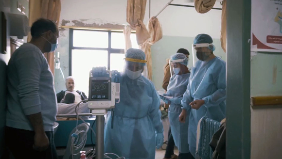 Medizinisches Personal mit Covid-19-Ausrüstung in einem Krankenhauszimmer 