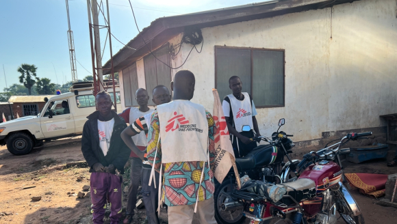 Fünf Männer in Ärzte ohne Grenzen Shirts neben Motorrädern
