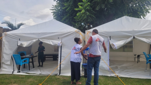 Zwei Mitarbeitende vor einem Zelt, in dem Cholera behandelt wird.