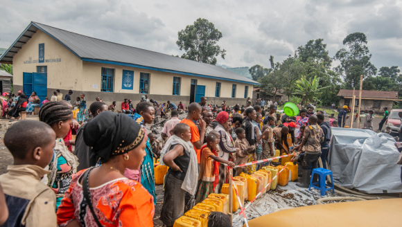 Viele Menschen, die aufgrund des Vulkanausbruchs in Goma flüchten mussten, stehen in einer Reihe, um sich Trinkwasser abzuholen. 