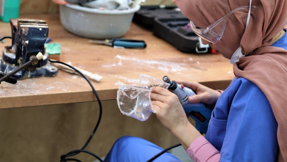 Eine Frau modelliert eine Kunststoffmaske mit einem Schleifgerät