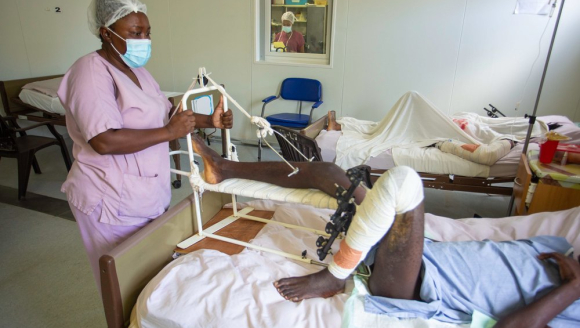 Eine Krankenpflegerin steht am Bett eines Patienten, der während des Erdbebens den Fuß gebrochen hat.