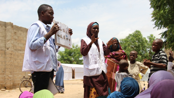 Mitarbeiter*innen der Gesundheitsförderung sprechen mit Vertriebenen in einem Camp in Borno