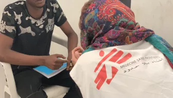 Arzt spricht mit Flüchtling in libyschem Internierungslager