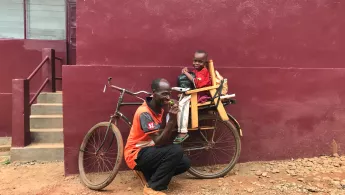 Der 8-jährige Dieu-Beni und sein Vater auf einem Fahrrad.