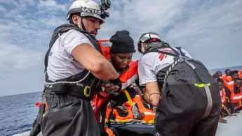 Zwei Mitarbeiter von Ärzte ohen Grenzen helfen den Menschen an Board der Geo Barents zu kommen