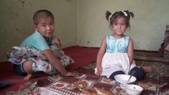Tuberkulose Bibisoleha und Zainidin Ein Junge und ein Mädchen sitzen auf dem Boden ihres Wohnhauses.