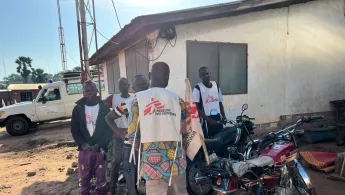 Fünf Männer in Ärzte ohne Grenzen Shirts neben Motorrädern