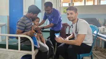 Junge sitzt auf dem Schoß seines Vaters während unsere Ärzte ihn behandeln.