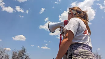 Eine Person von hinten in Ärzte ohne Grenzen Shirt mit Megaphone