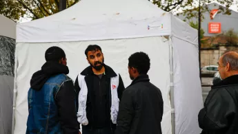 Migranten und ein Mitarbeiter vor einer mobilen Klinik in Calais