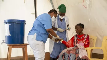 Unsere Pflegerinnen versorgen eine Patientin im Triage-Zelt unseres Cholera-Behandlungszentrums in Bujumbura, Burundi. Wir übernehmen die Diagnose und Erstversorgung der Patient*innen. Pflegerinnen versorgen Patientin in Cholera-Behandlungszelt