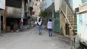 Zwei Mitarbeitende laufen durch zerstörte Straßen