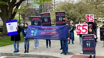 Gruppe Menschen hält Schilder mit Forderung an Danaher Preis zu senken