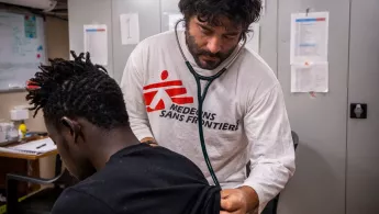 Unser Arzt Juan Pablo während einer der medizinischen Konsultationen an Bord der Ocean Viking. Mitarbeiter hört Patient mit Stethoskop ab