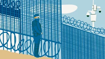 Im Grenzgebiet zwischen Frankreich und Großbritannien sitzen Menschen fest. Uniformierter Mann steht vor einem Stacheldrahtzaun