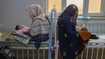 Zwei Frauen sitzen mit ihren Babys auf dem Schoss auf Betten