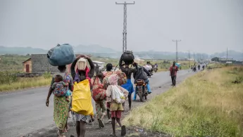 D. R. Kongo: Menschen laufen an Straßenrand mit Gepäck beladen