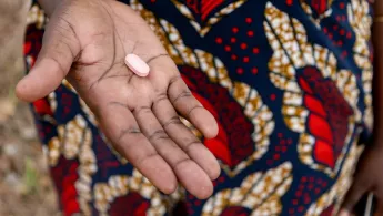 Eine Tablette liegt in der offenen Hand einer Patientin.