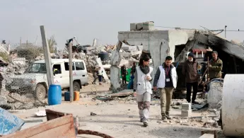 Gaza Blockade: Mitarbeitende laufen zwischen zerstörten Gebäuden