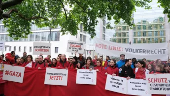 Menschen mit Plakaten demonstrieren vor Auswärtigem Amt