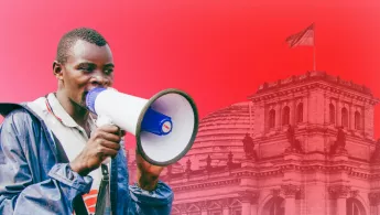 Mitarbeitender mit Megaphon vor rotem Hintergrund mit Bundestag