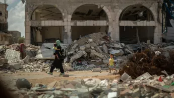 Frau trägt Kind durch Trümmer in Gaza-Stadt.