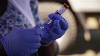 Masernimpfung wird aus Ampulle von Mitarbeiter entnommen.