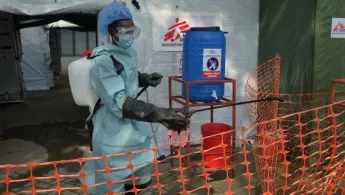 Mitarbeiter in Schutzkleidung vor Behandlungszelt