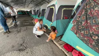 Kniende Mitarbeitende spricht mit Kind