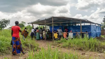 Menschen stehen vor Hütte aus Planen