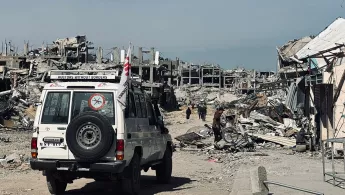 Geländewagen mit Ärzte ohne Grenzen Logo vor zerstörten Gebäuden