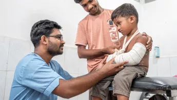 Ein kleiner Junge mit eingegipsten Arm wird behandelt.