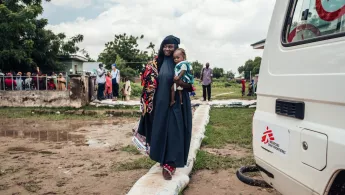 Frau trägt Töchter auf Arm