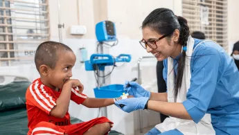 Ein kleiner Junge wird von einer Krankenschwester behandelt - beide lachen.