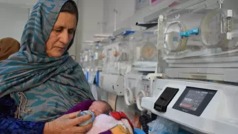 Frau füttert Baby mit Flasche auf Krankenstation