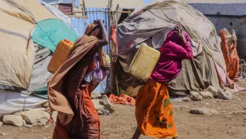 Zwei Frauen tragen Wasserkanister in Camp