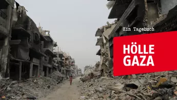 Zerstörte Straße und Gebäude darüber Schriftbanner Hölle Gaza