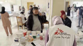 Eine Mitarbeiterin gibt Medikamente an Patient*innen aus.