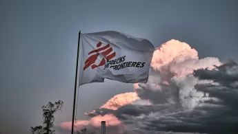 Flagge mit Logo von Ärzte ohne Grenzen vor bewölktem Himmel