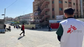 Einer unser Mitarbeitendena steht vor dem Nasser-Krankenhaus