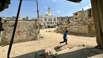 Ein Junge rennt durch eine zerstörte Stadt.