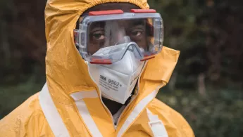 Eine Person trägt einen Schutzanzug mit FFP3 Atemschutzmaske und Sicherheitsbrille