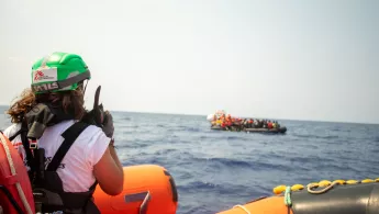 Mitarbeitende auf Schlauchboot spricht in Funkgerät