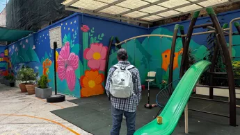 Ein Mann steht mit einem Rucksack neben einer grünen Rutsche.