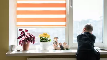 Ein Junge lehnt an einer Fensterbank und schaut aus dem Fenster